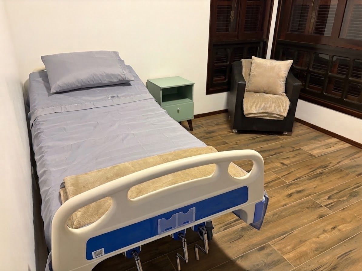 Quarto privativo com cama hospitalar e poltrona