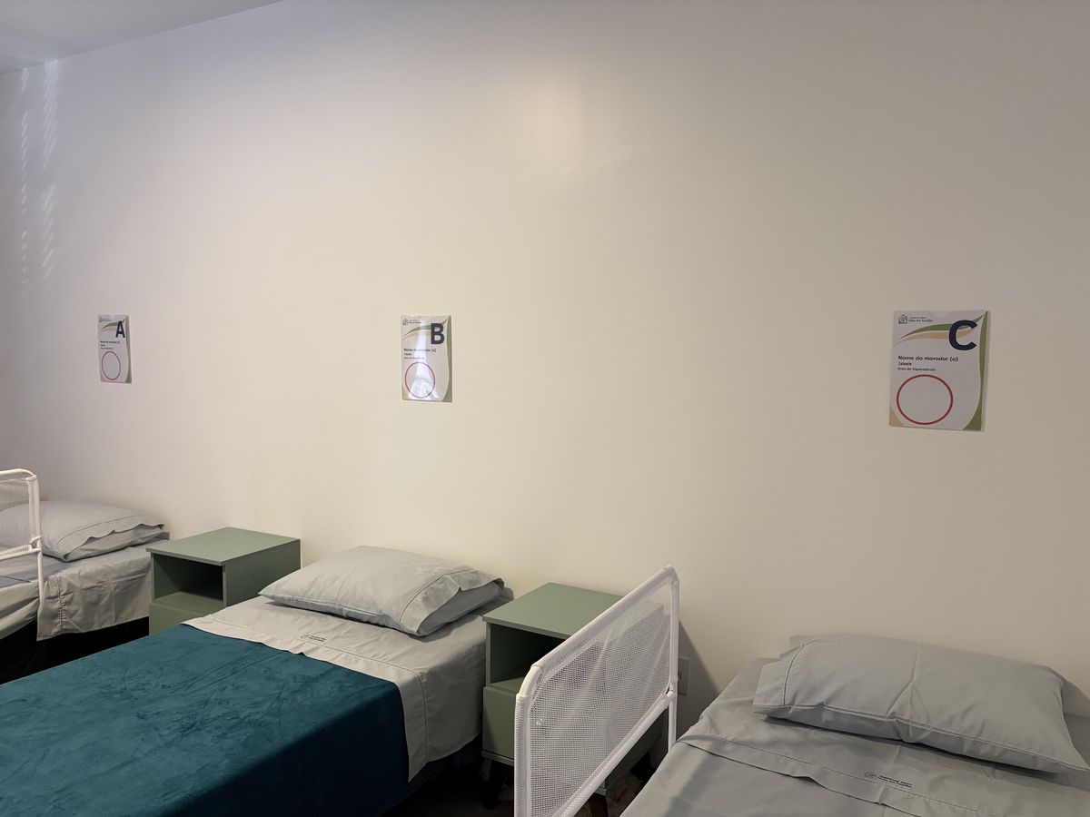 Quarto com camas identificadas por residente e grades de proteção