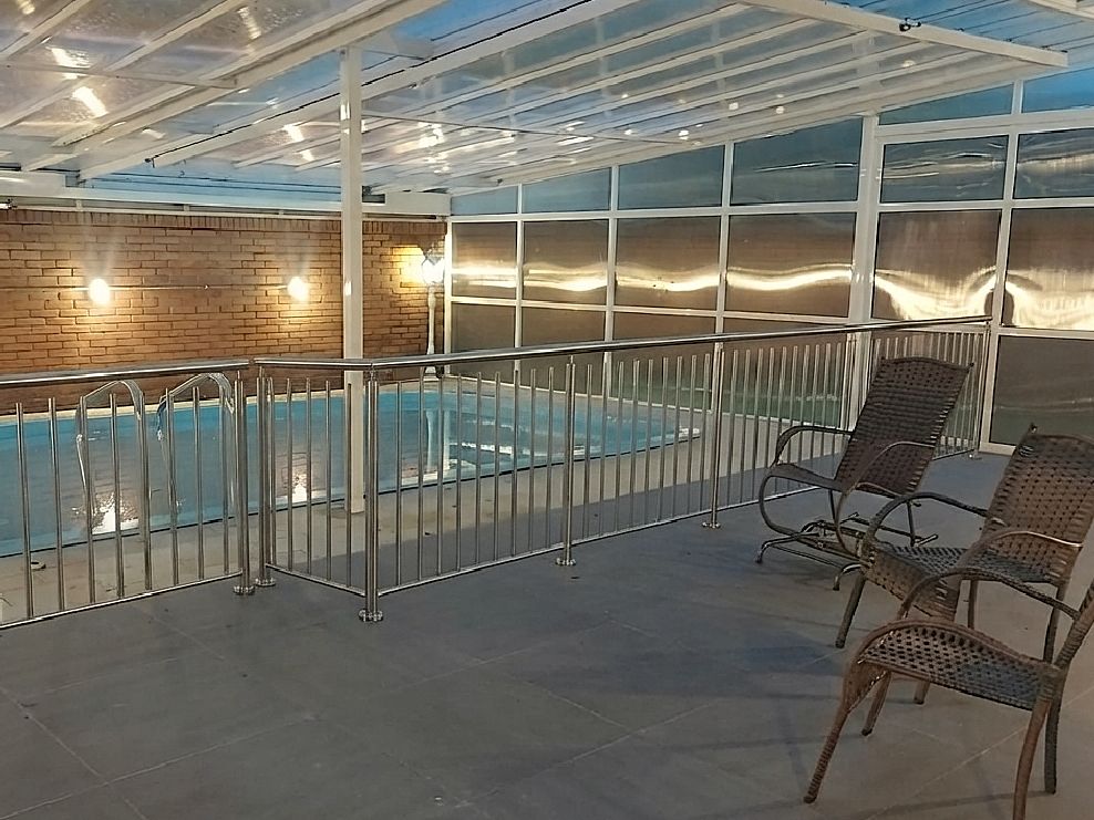Piscina coberta com grade de proteção e área de descanso